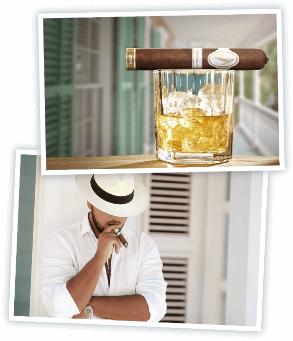 Eine Davidoff Dominicana Robusto Zigarre liegt auf einem Glas Rum auf einer Veranda und ein in Weiss gekleideter Mann mit dominikanischem Hut raucht eine Davidoff Dominicana Zigarre
